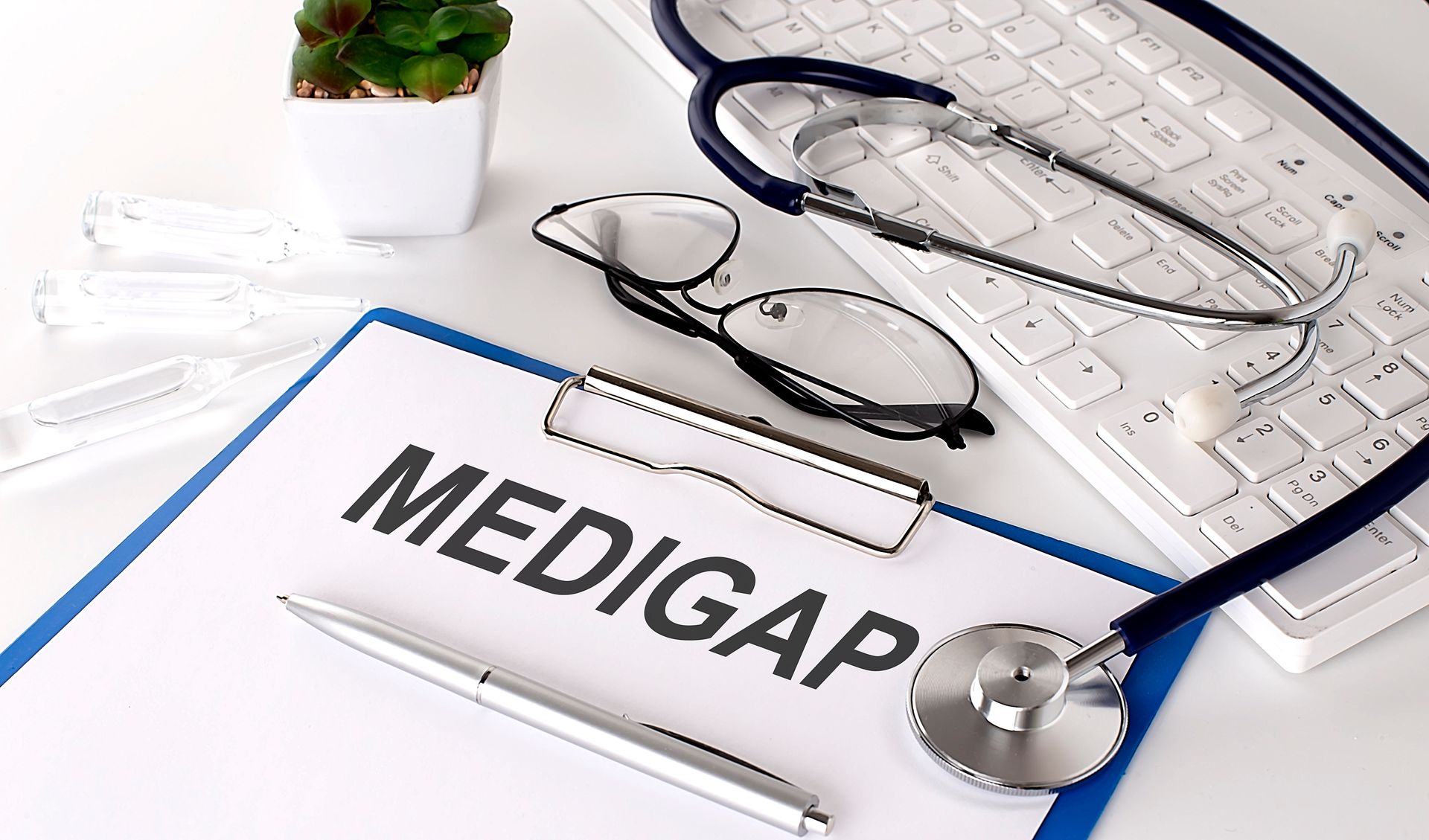Doctor's desk with stethoscope, eyeglasses, keyboard, and a clipboard labeled “MEDIGAP”