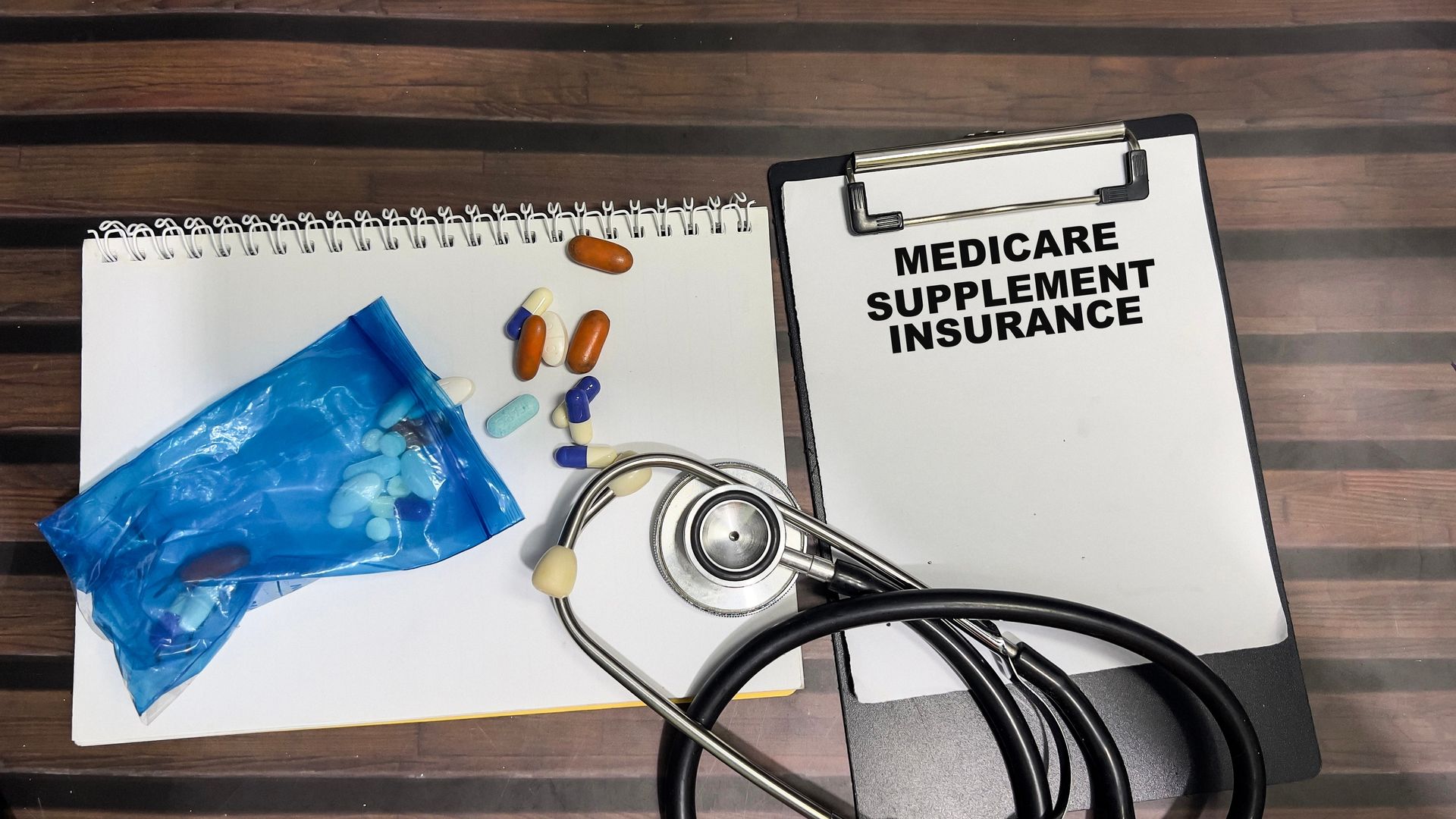 Medicade supplement insurance notebook with stethoscope, pills, and blue tissue pack