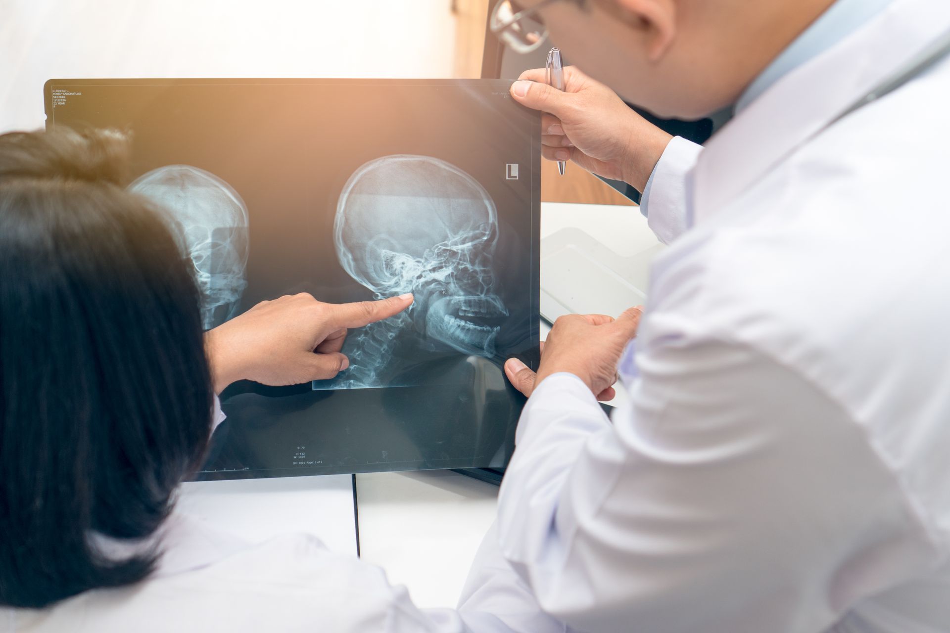 Two medical professionals reviewing brain X-rays on a lightbox and pointing at one scan