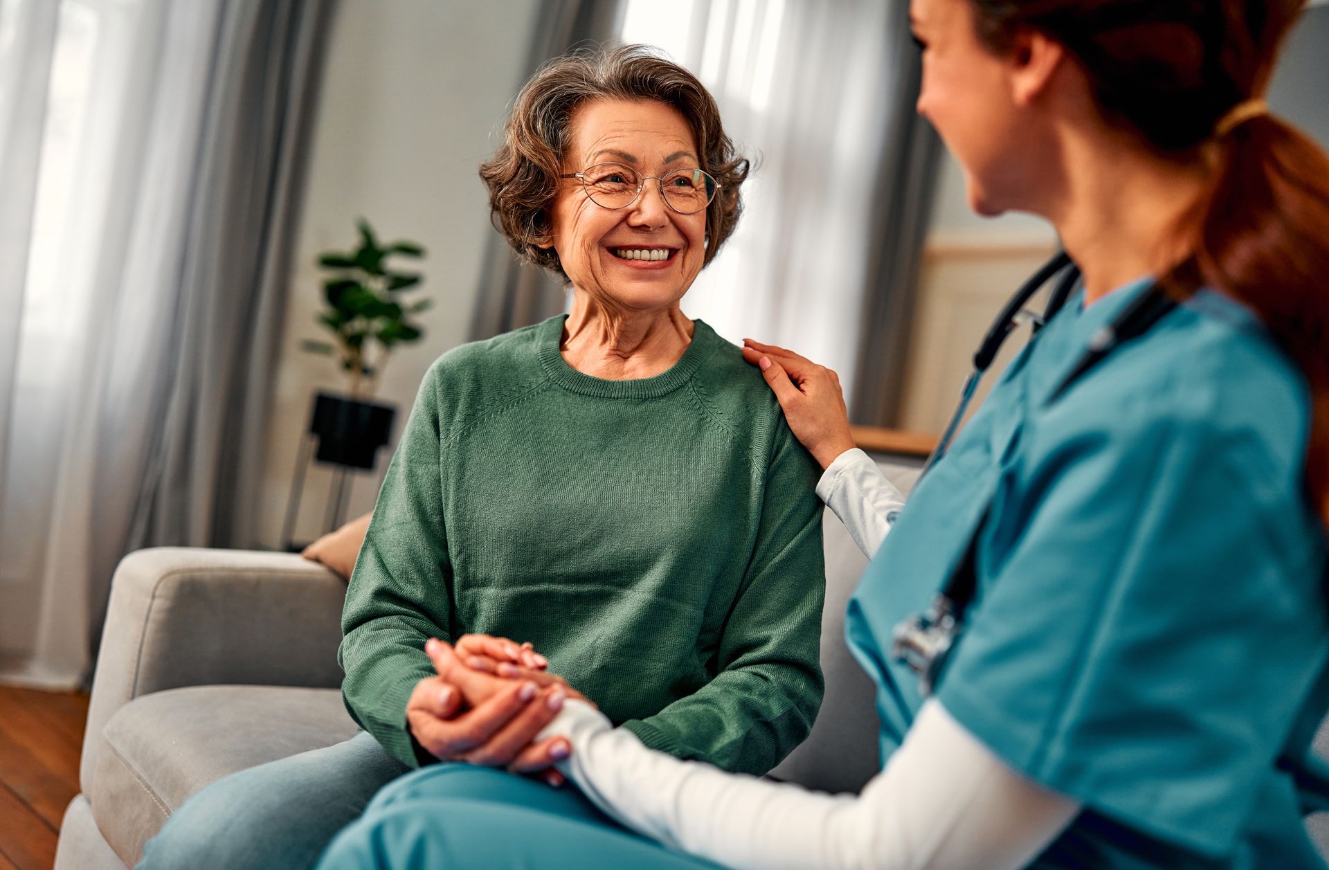 Healthcare worker talking with a smiling patient on a couch in a bright living room