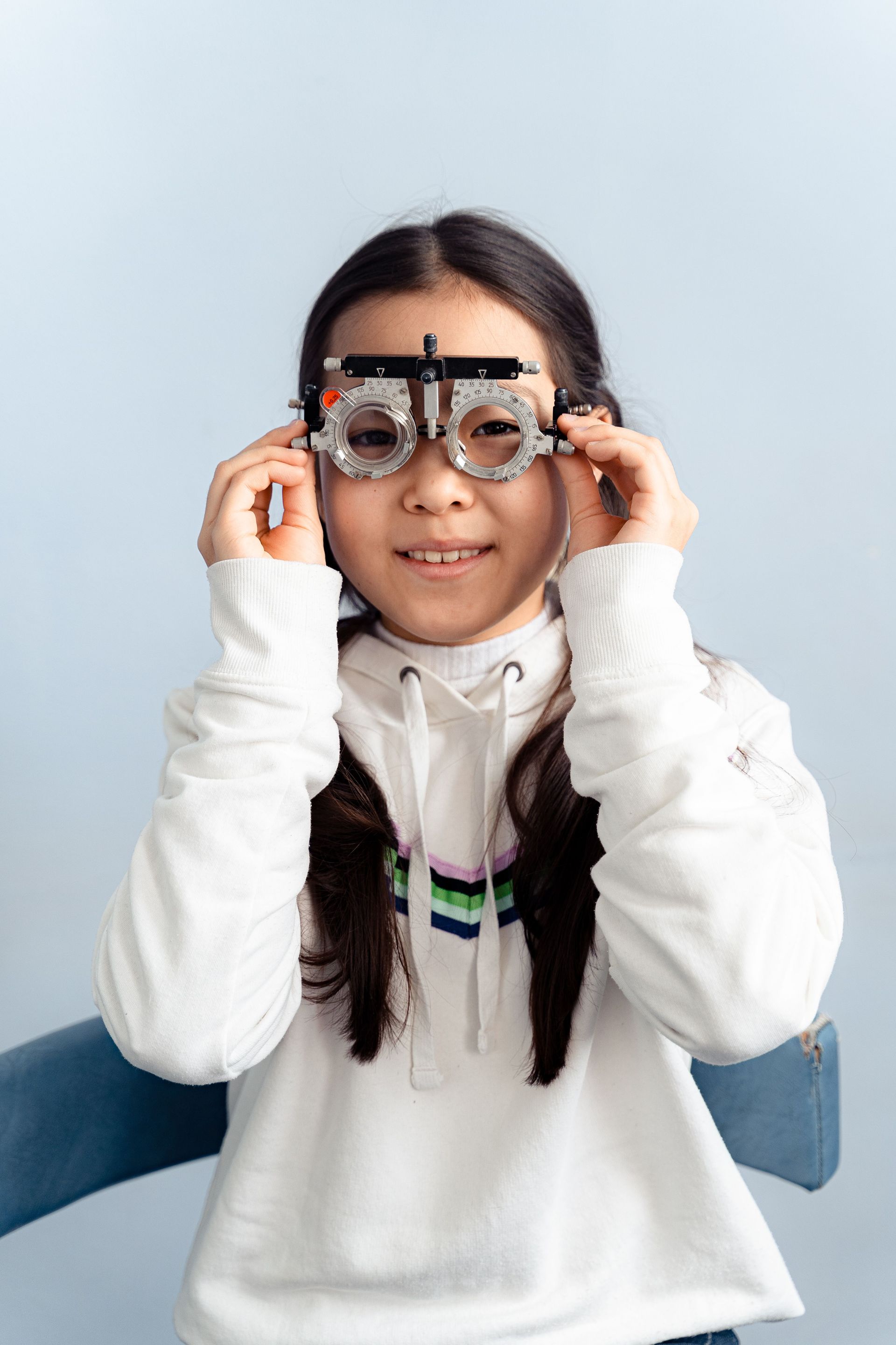 Child holding up a pair of glasses and smiling against a light blue background
