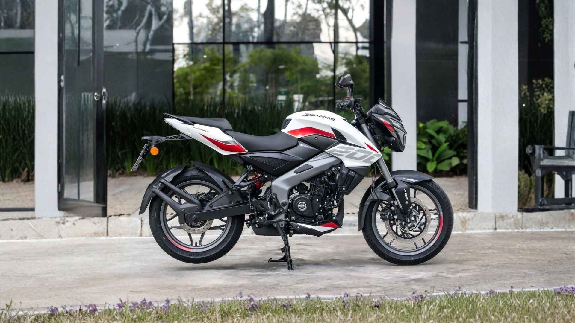 White and red sport motorcycle parked on a sidewalk outside a glass-fronted building.