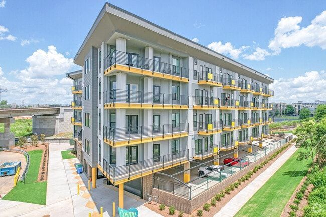 Modern apartment building with yellow accents and balconies, under a blue sky.