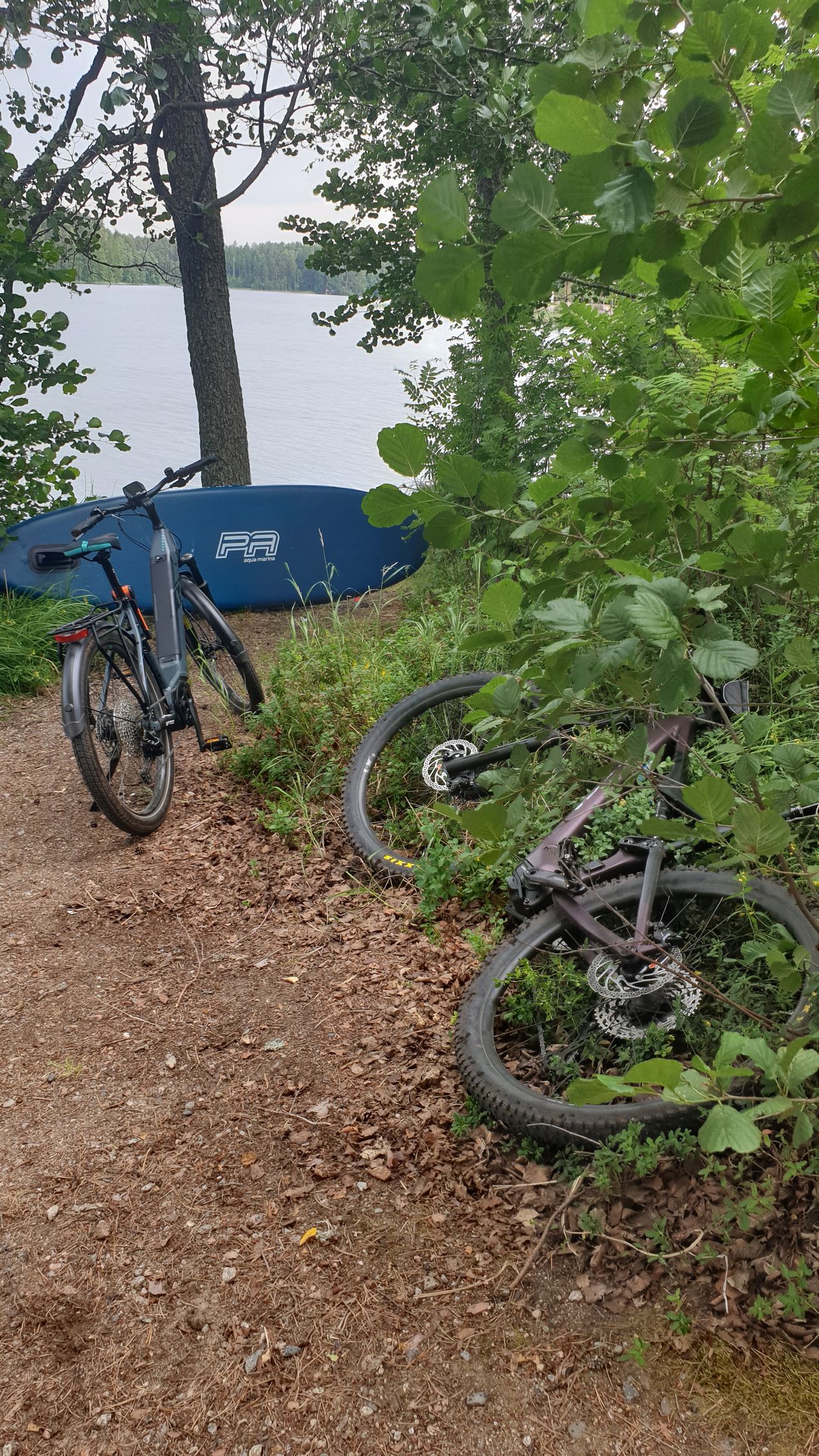 A bicycle is parked on a dirt path next to a lake.