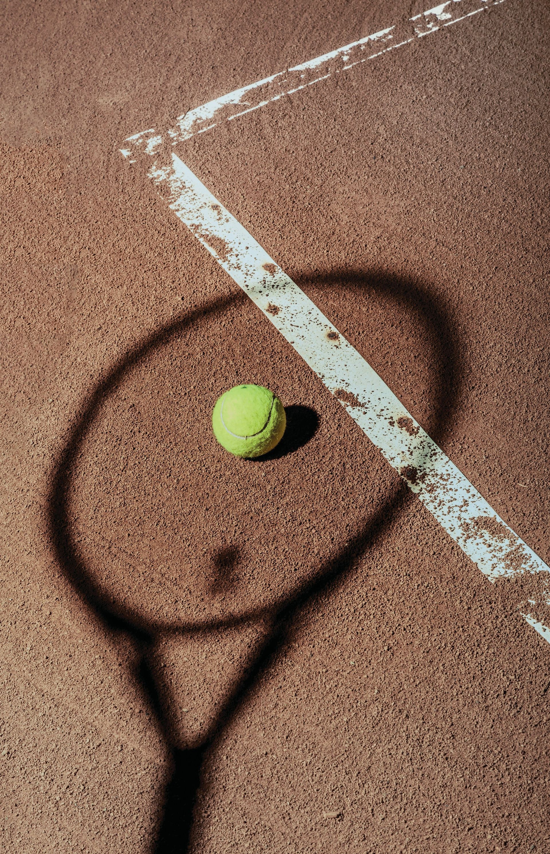 A tennis ball is sitting on top of a tennis racket on a tennis court.