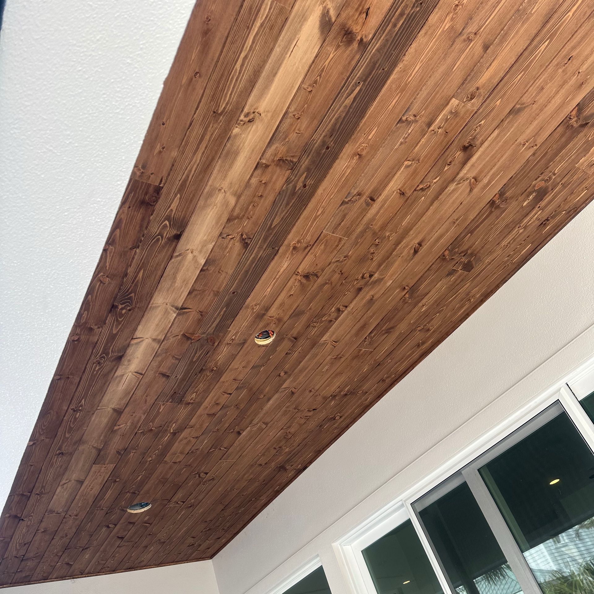 A wooden ceiling with a window in the background