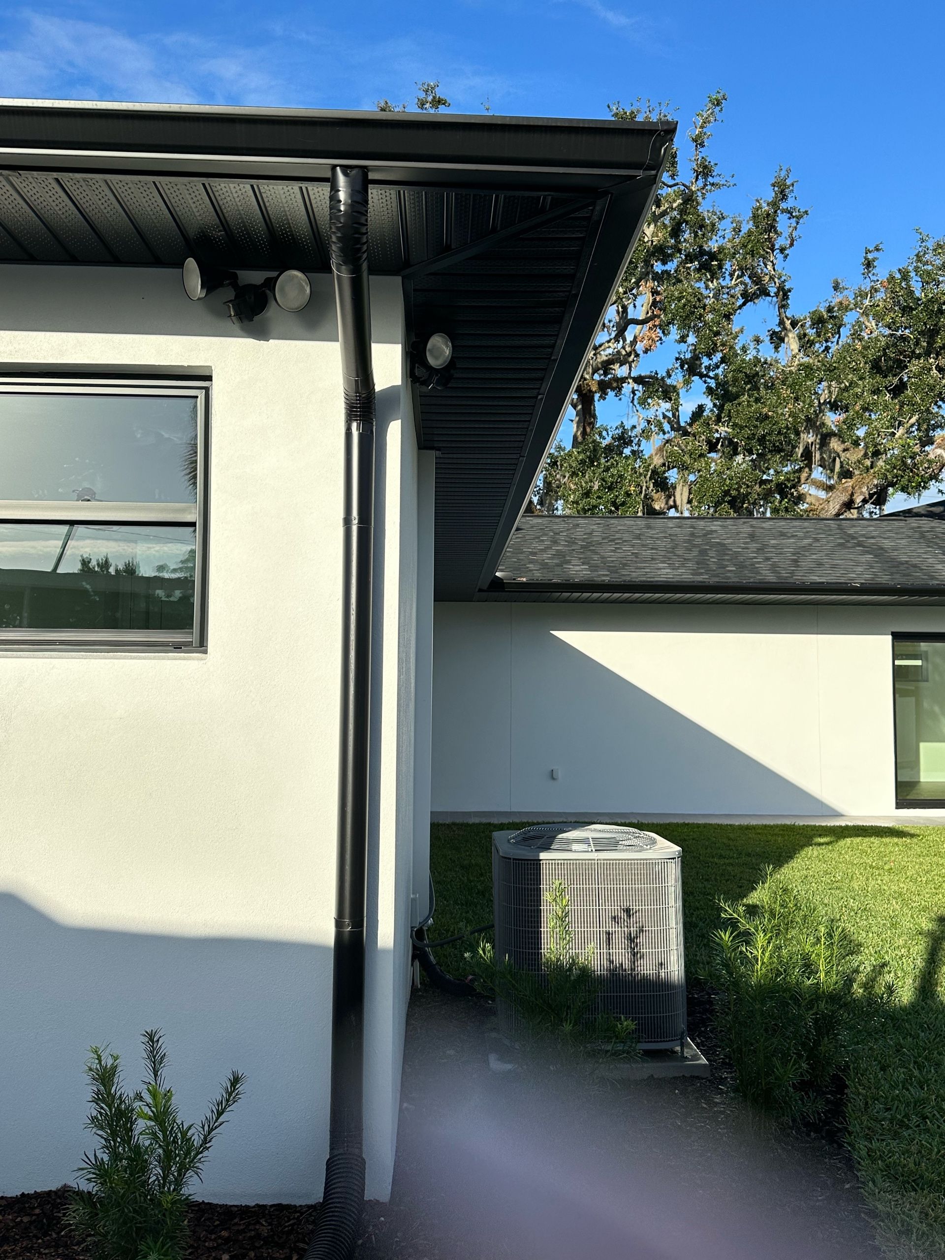 A white house with a black gutter and a black roof.