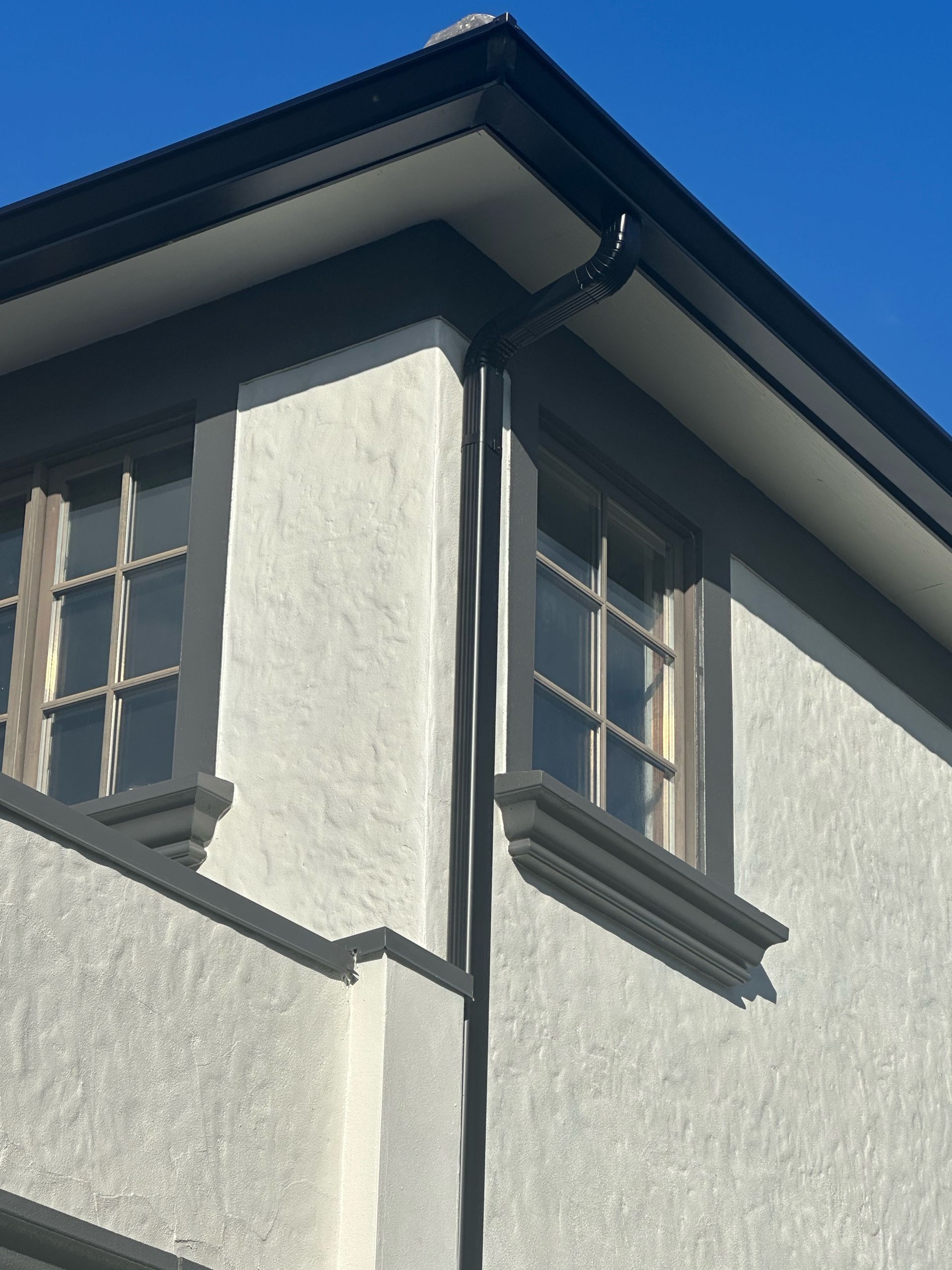 A white building with a black gutter on the corner