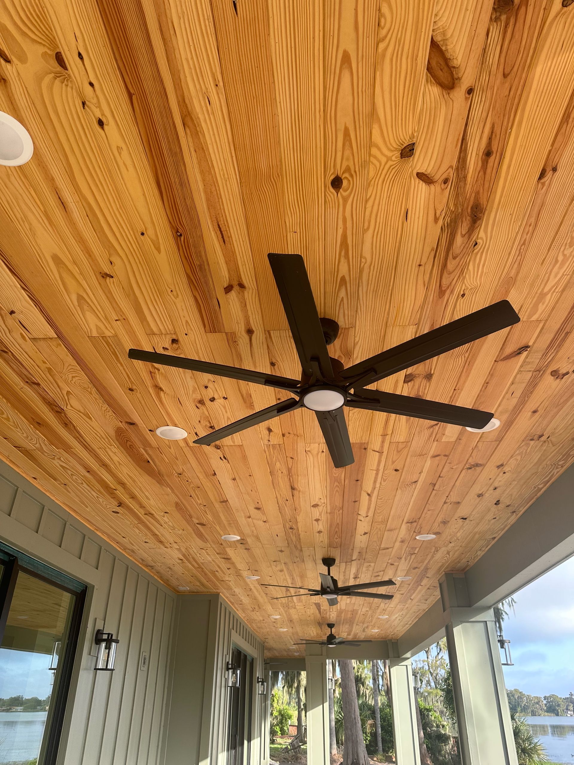 A ceiling fan is hanging from the ceiling of a porch.