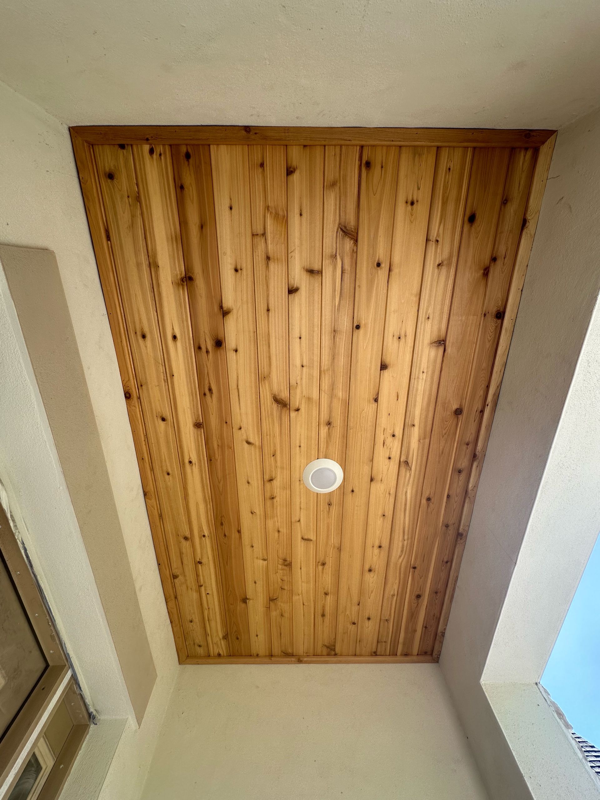A wooden ceiling with a light on it in a room.