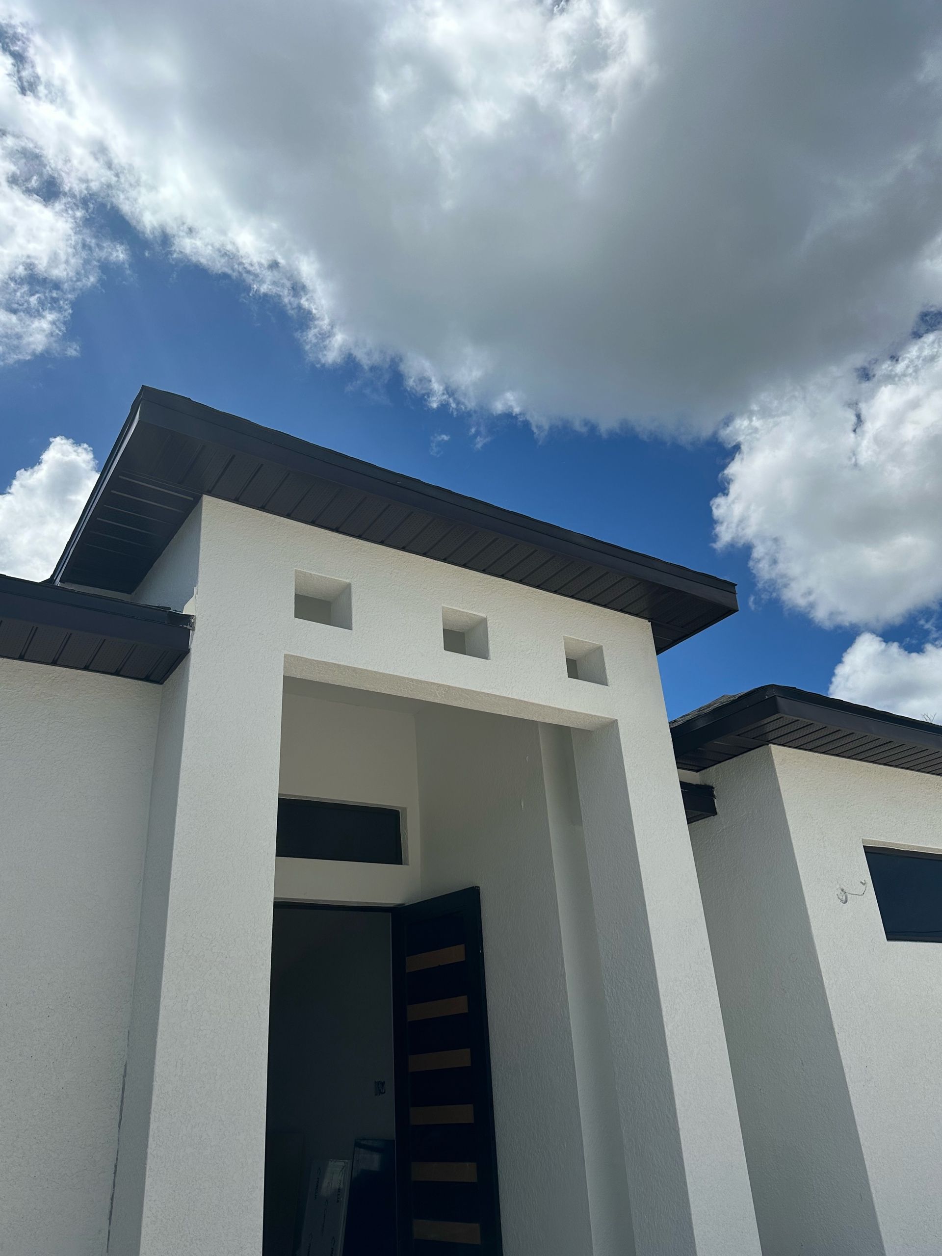 A white house with a blue sky and clouds behind it