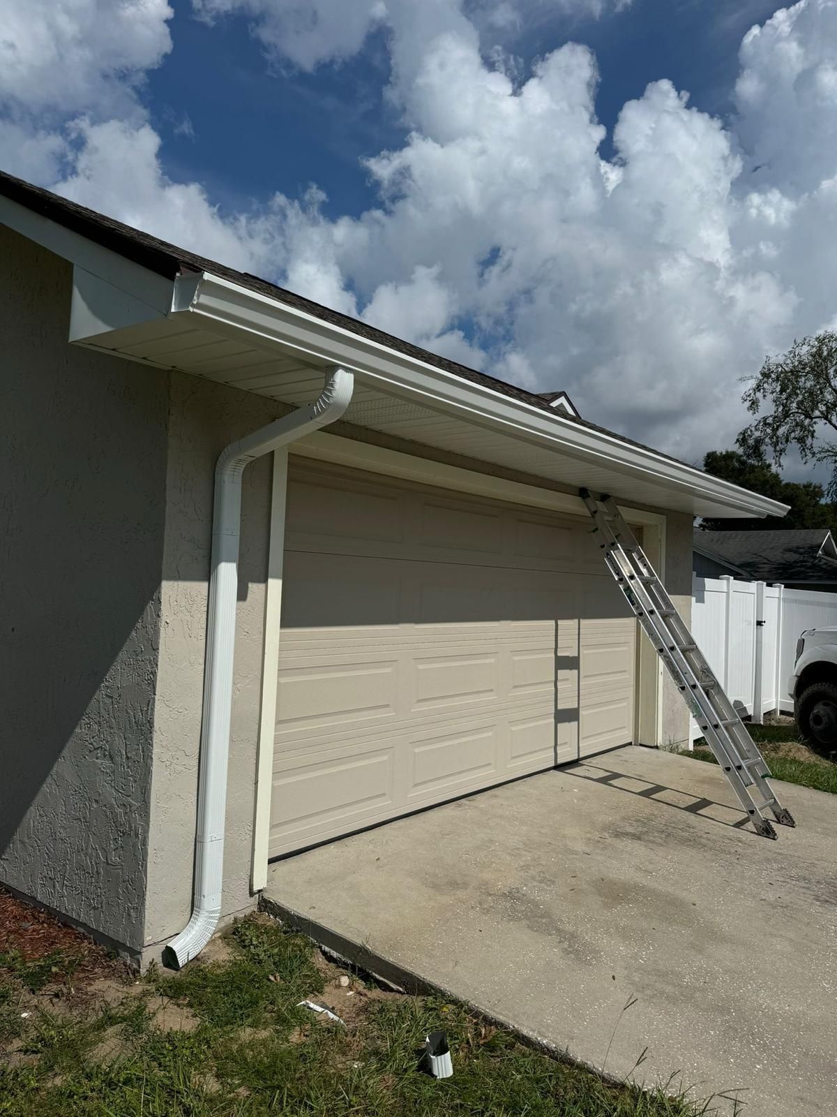 A house with a garage door and a ladder in front of it.