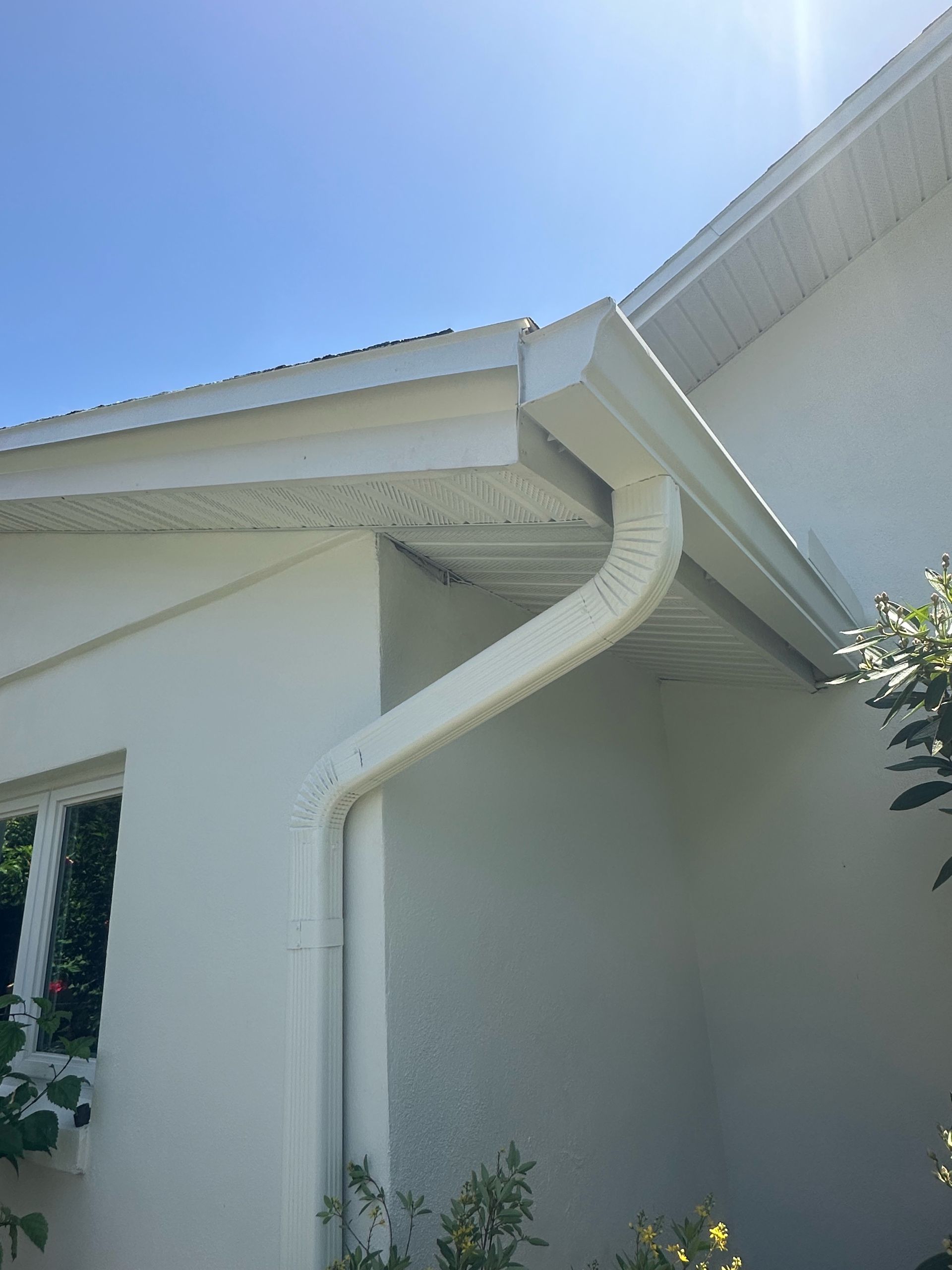 A white house with a white gutter on the side of it.