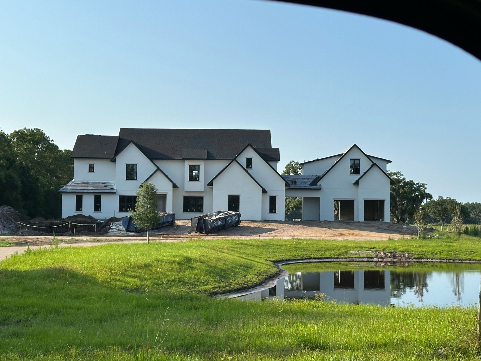 A large white house with a black roof is under construction
