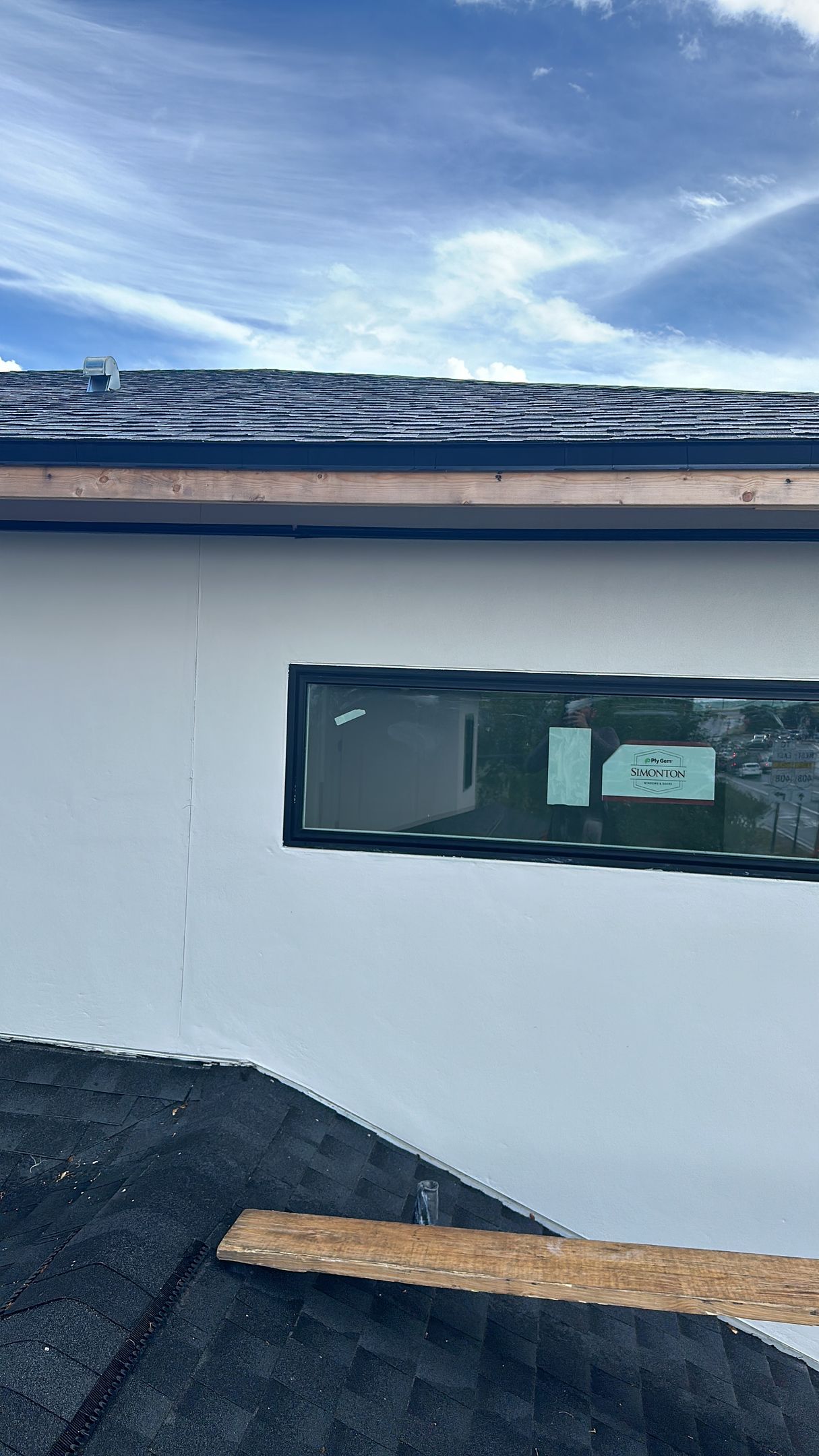 A white house with a black roof and a window on the side.