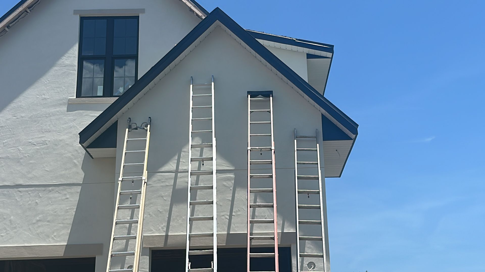 Three ladders are lined up on the side of a house
