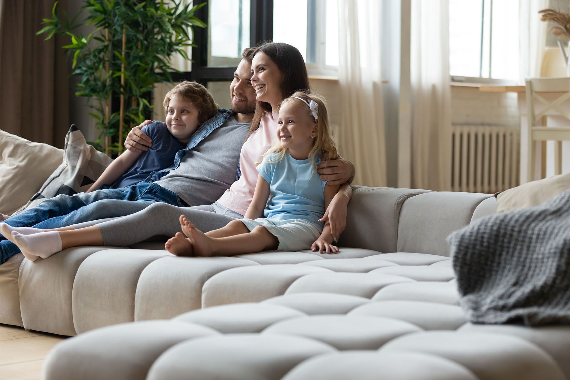 Family sitting together on a white sofa in a bright living room. Family sitting together on a white sofa in a bright living room.