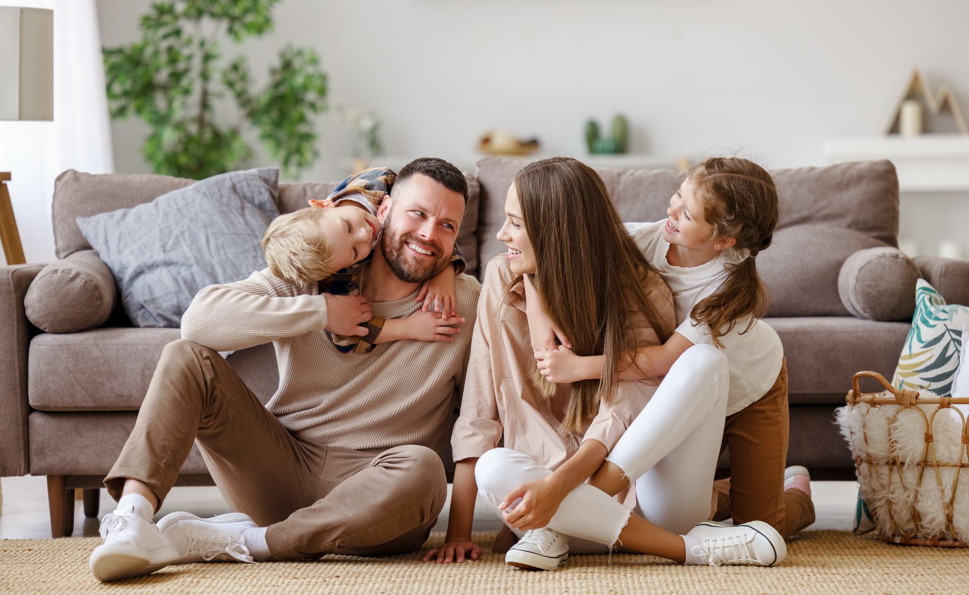 Family cuddling on a couch with a toddler, smiling in a cozy living room.