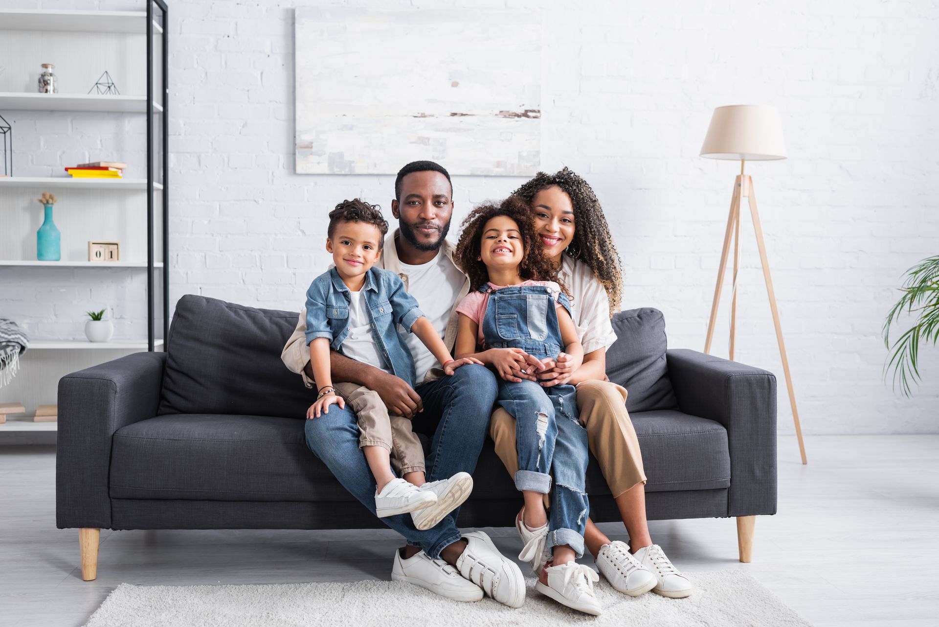 Family sitting together on a dark gray sofa in a bright living room