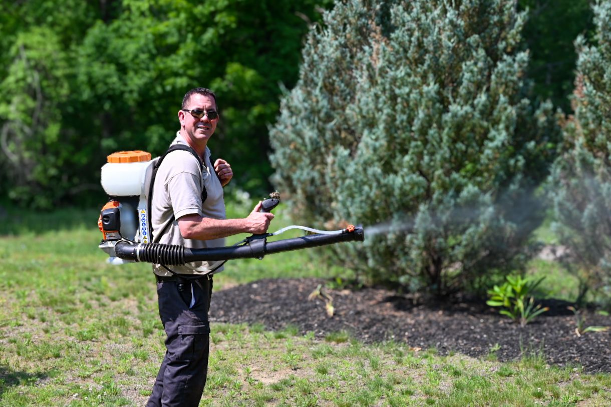 a man wearing sunglasses and a backpack sprayer.