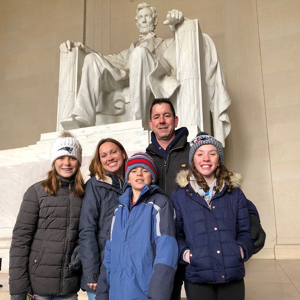 Family of five posing indoors in winter clothes beneath the Lincoln Memorial statue