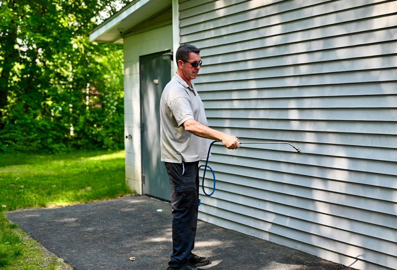 Technician applying treatment on a home's vinyl siding.