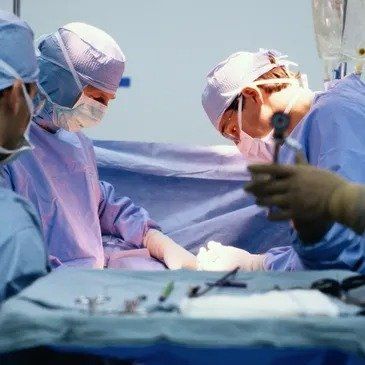 A group of surgeons are operating on a patient in an operating room.