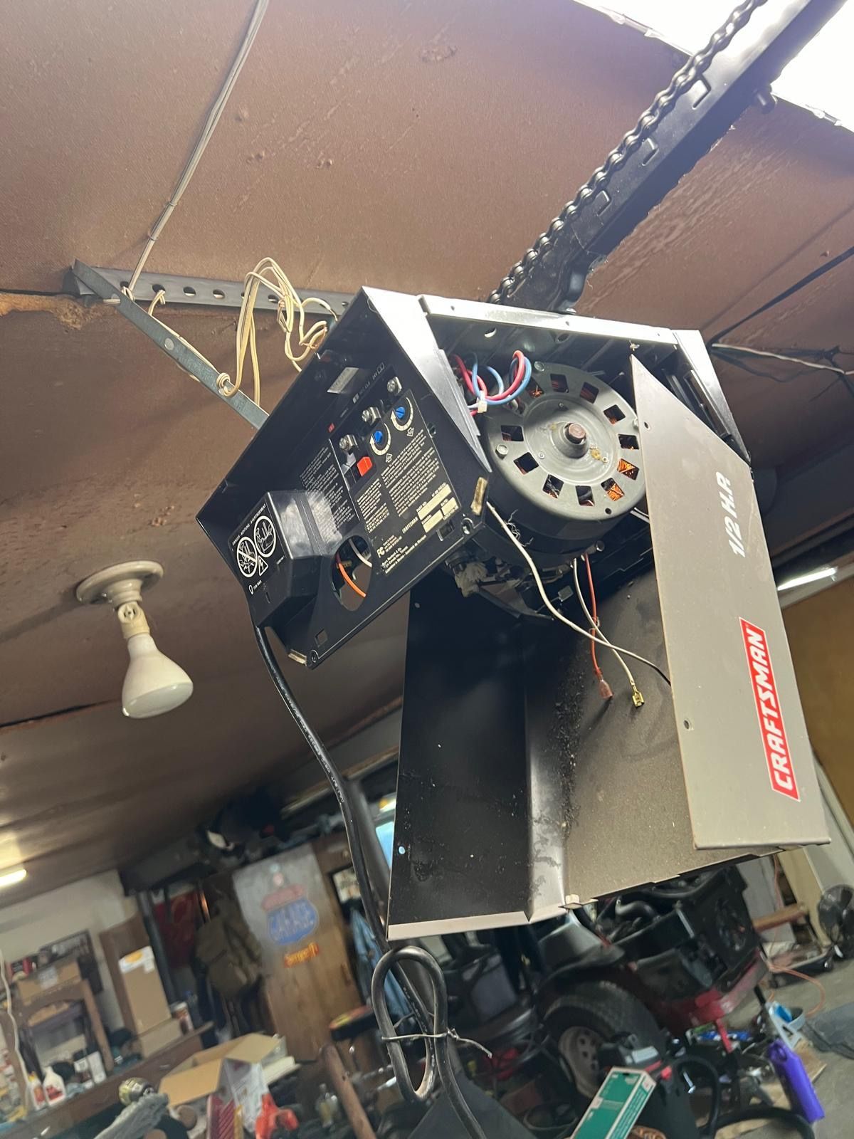 Garage door opener, black box attached to the ceiling, with visible wires and motor.