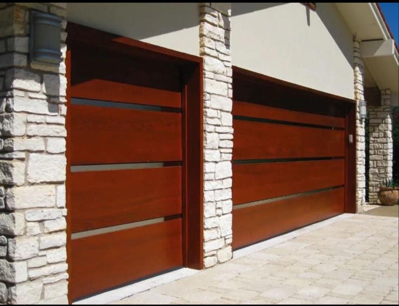 Two brown garage doors with horizontal glass insets, flanked by stone columns.