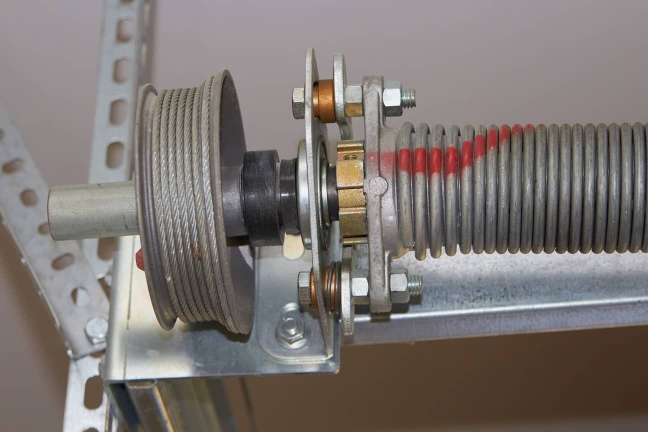 Garage door torsion spring and cable system, mounted on metal brackets.