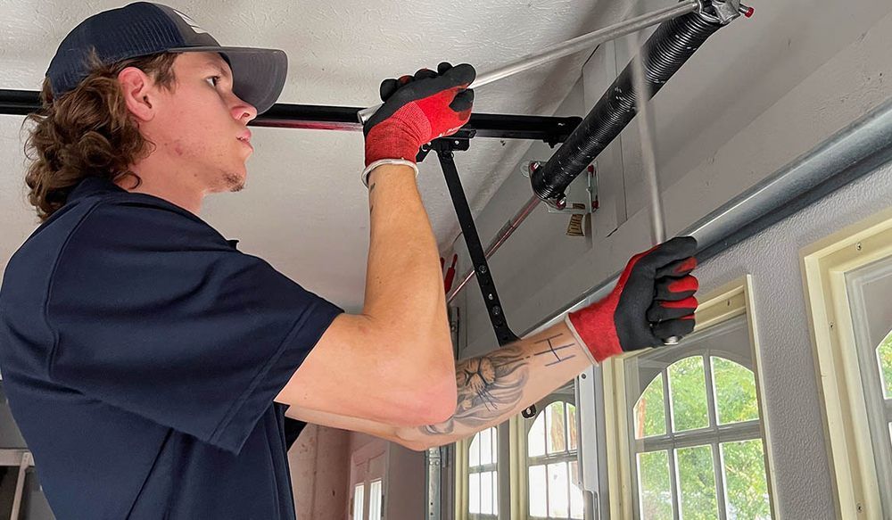 Person in gloves working on garage door springs.
