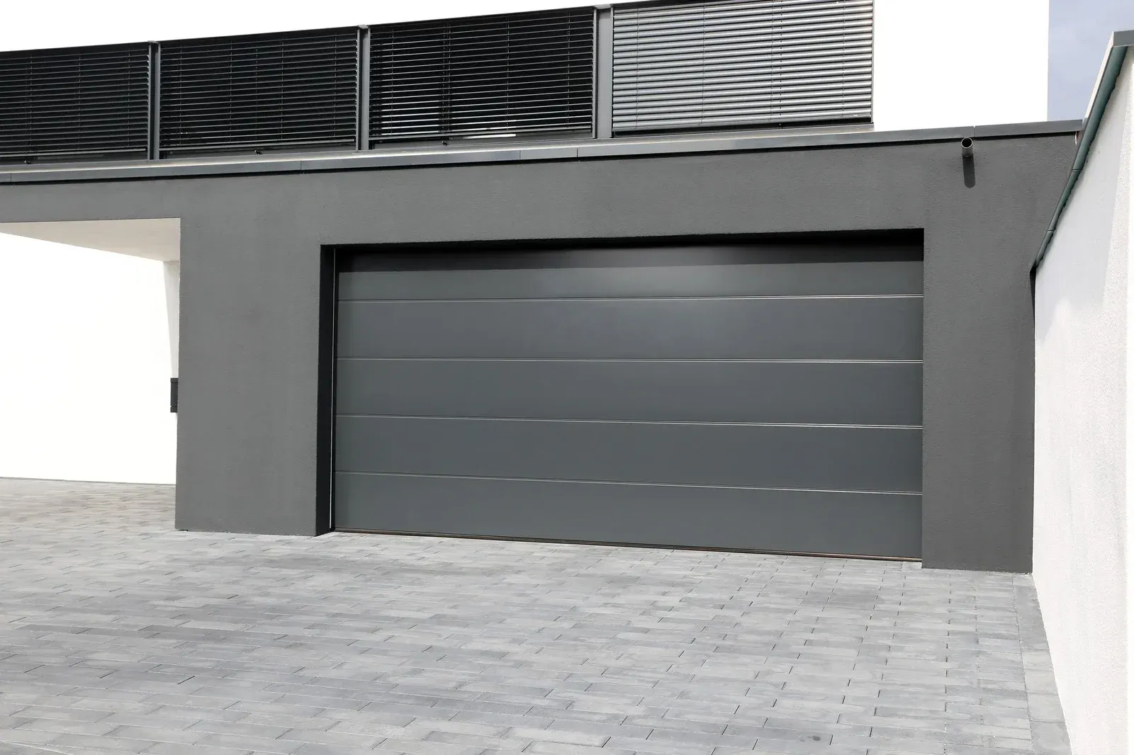 Gray garage door in a gray garage with a paved driveway.