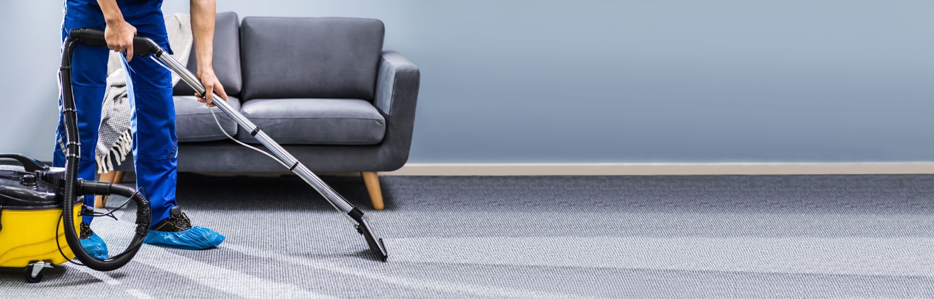 Professional carpet cleaning with a vacuum wand in a modern living room.