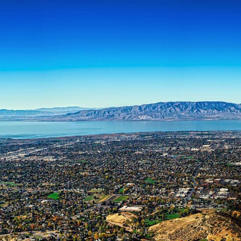Cityscape with blue lake and mountains under a clear blue sky. Cityscape with blue lake and mountains under a clear blue sky.