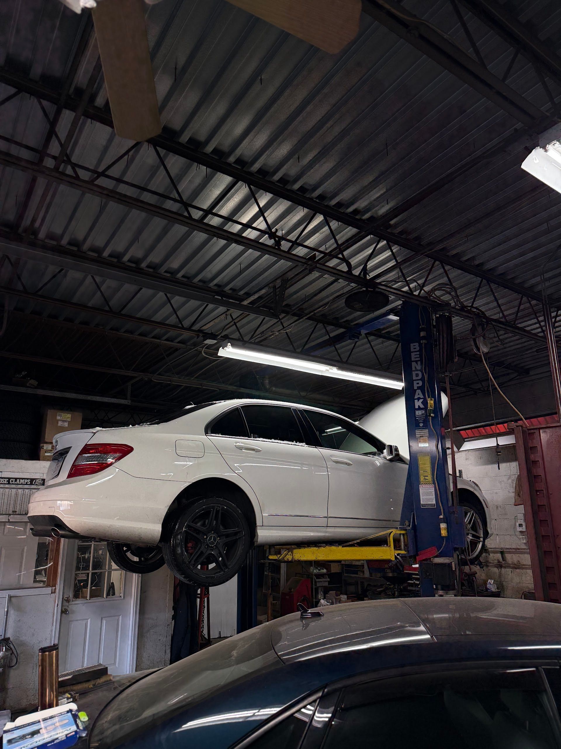 White Car Raised On Lift In Repair Bay | C&Z Auto Repairs