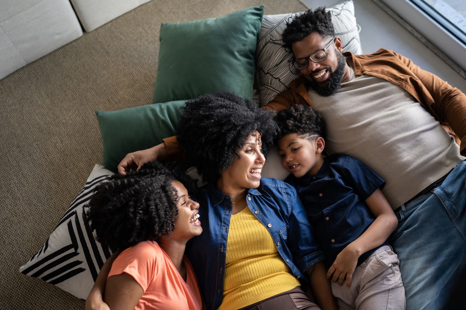 A family is laying on the floor on a couch.