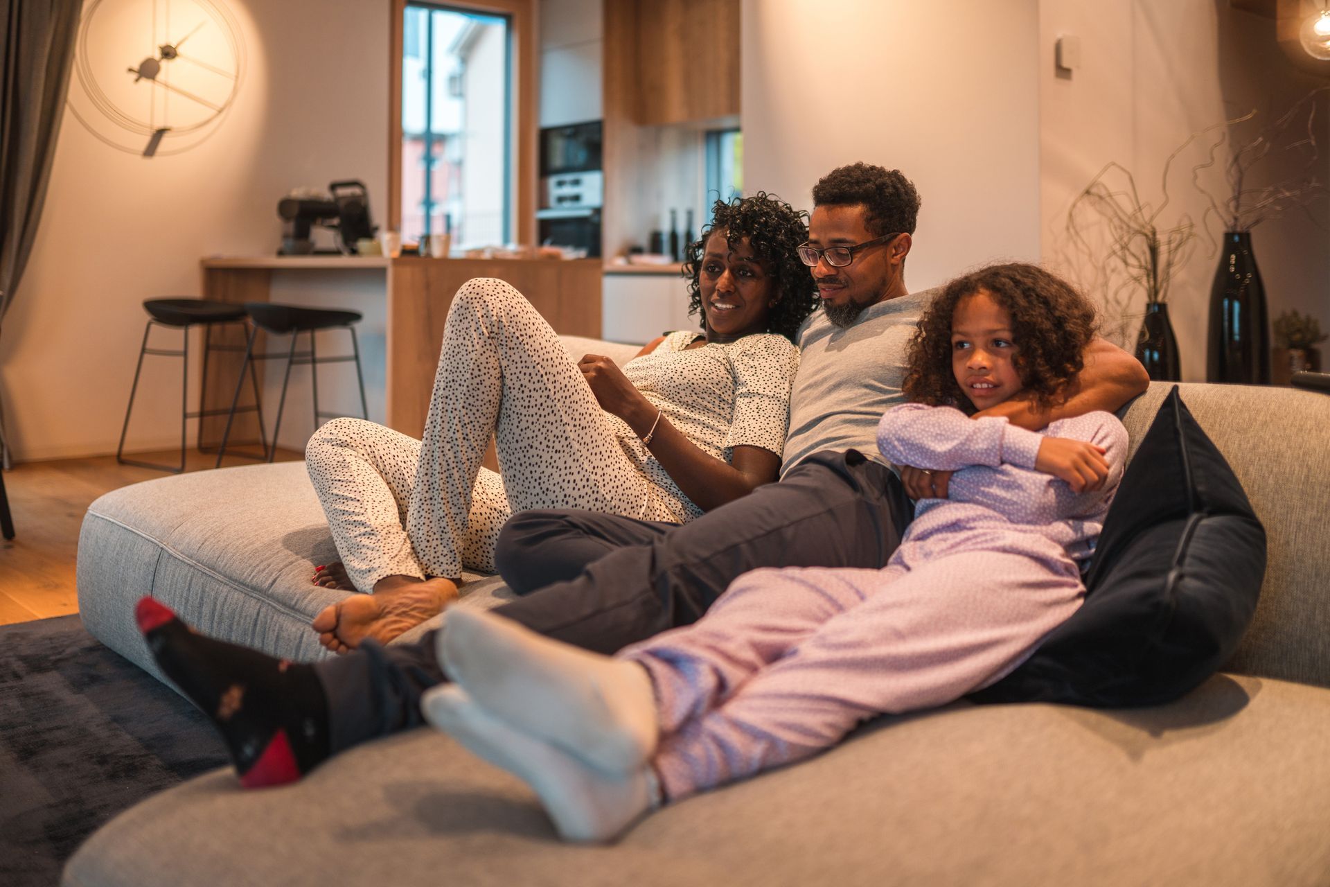 A family is sitting on a couch watching tv.