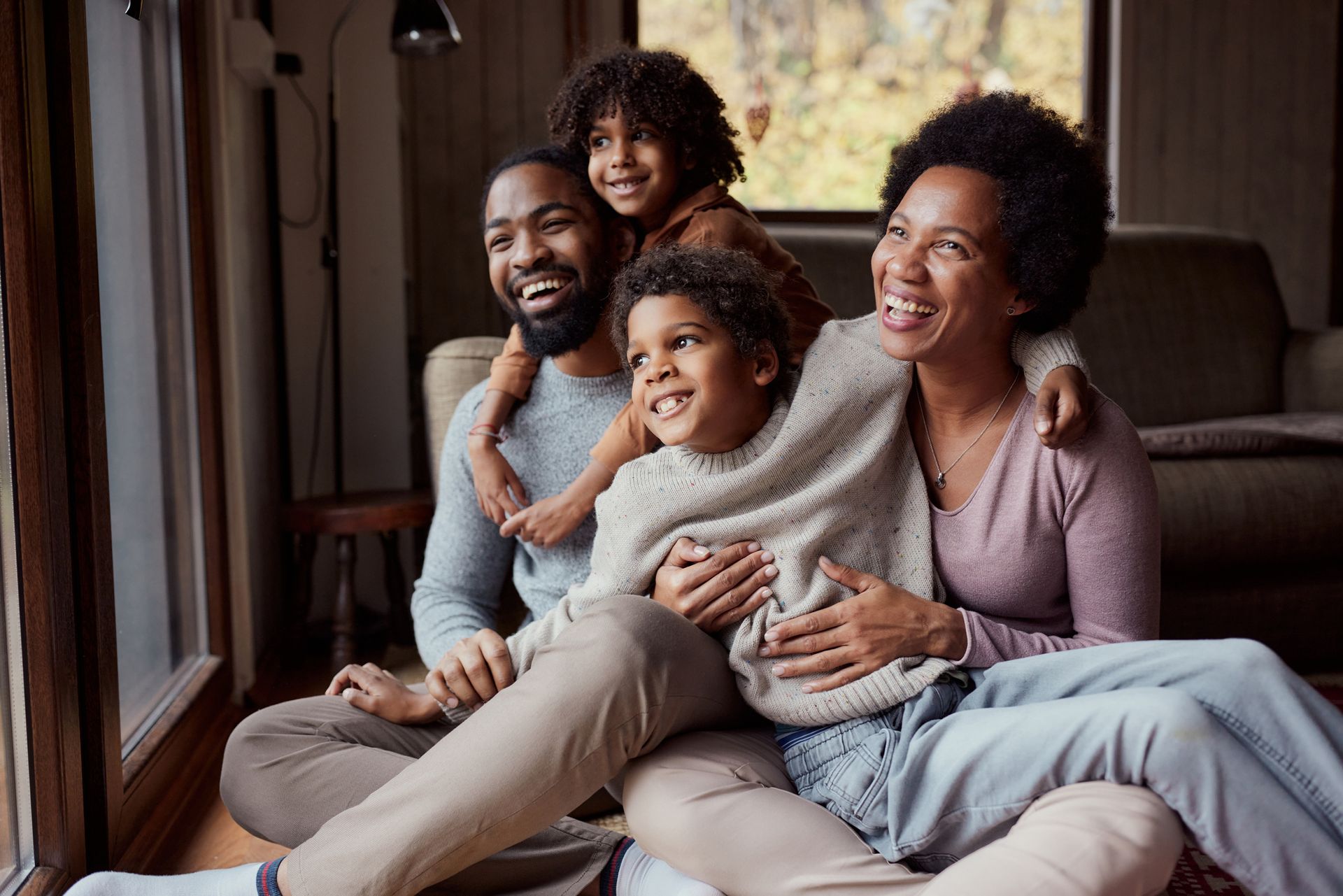 A family is sitting on the floor in front of a window.
