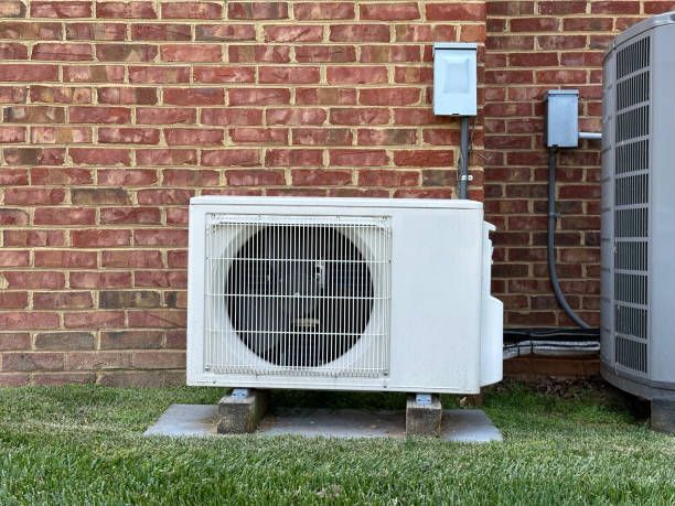 A white air conditioner is sitting outside of a brick building.