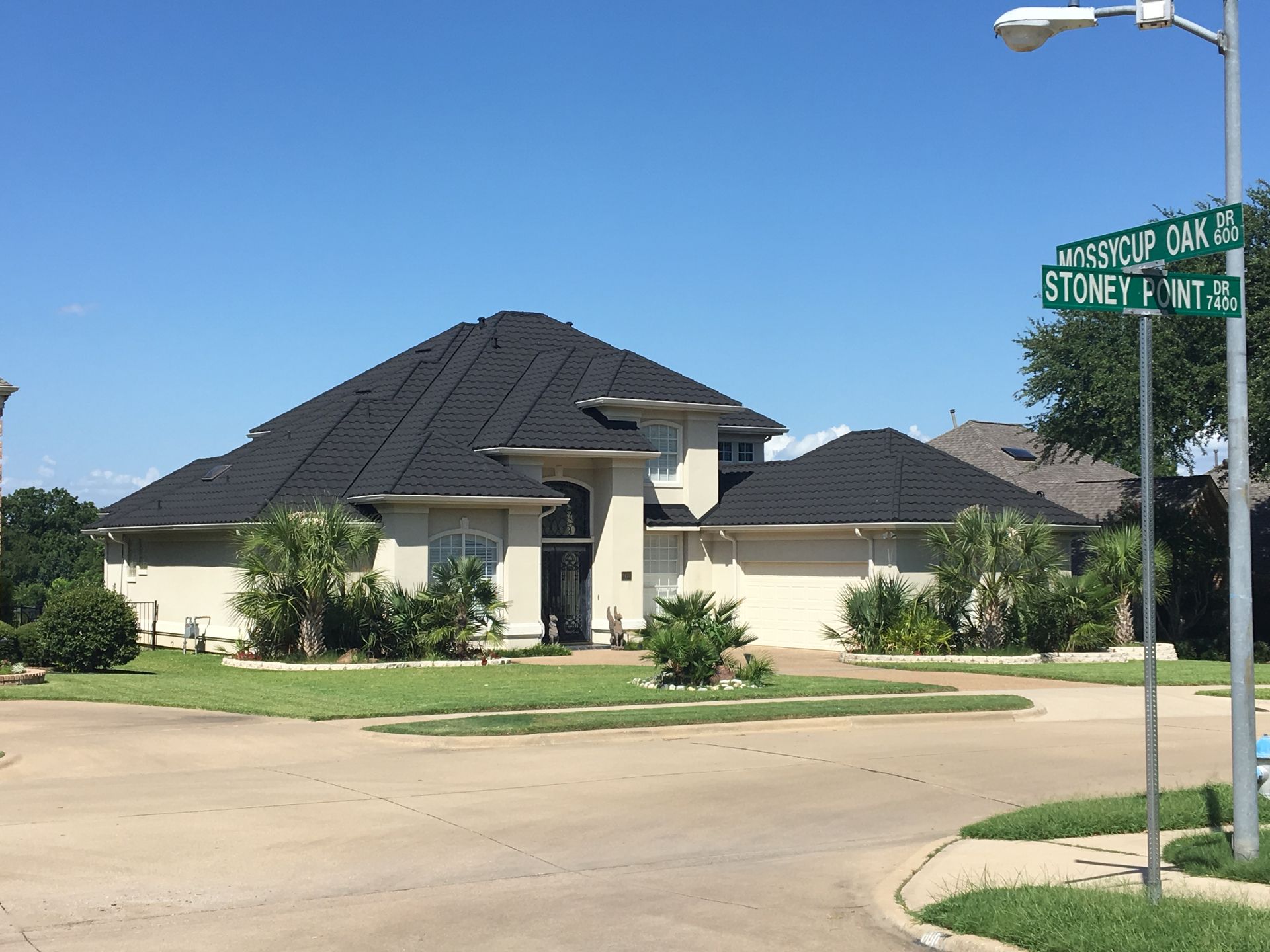 Aerial view of a house with a brown shingle roof and surrounding yard.