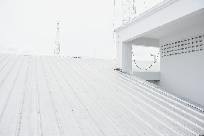 Bright white rooftop terrace with railings and a small covered seating area.