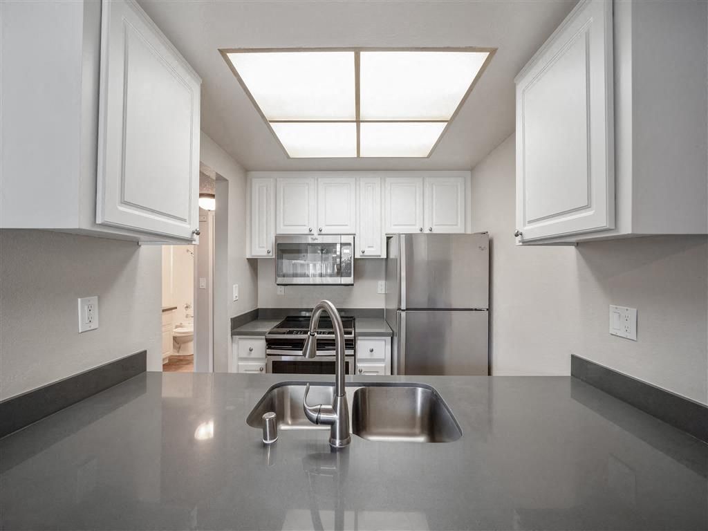 Kitchen in an apartment with white cabinets, stainless steel appliances, and a centered sink at Valley Ridge Apartments.