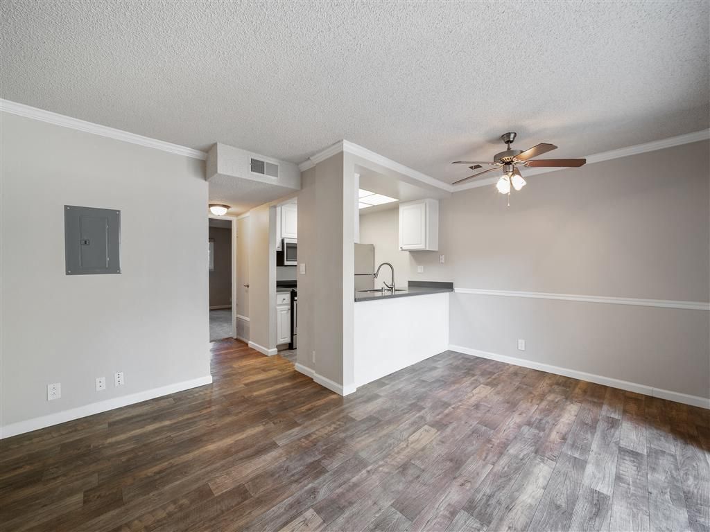 Open living area with kitchen pass-through, ceiling fan, and wood-look flooring at Valley Ridge Apartments.