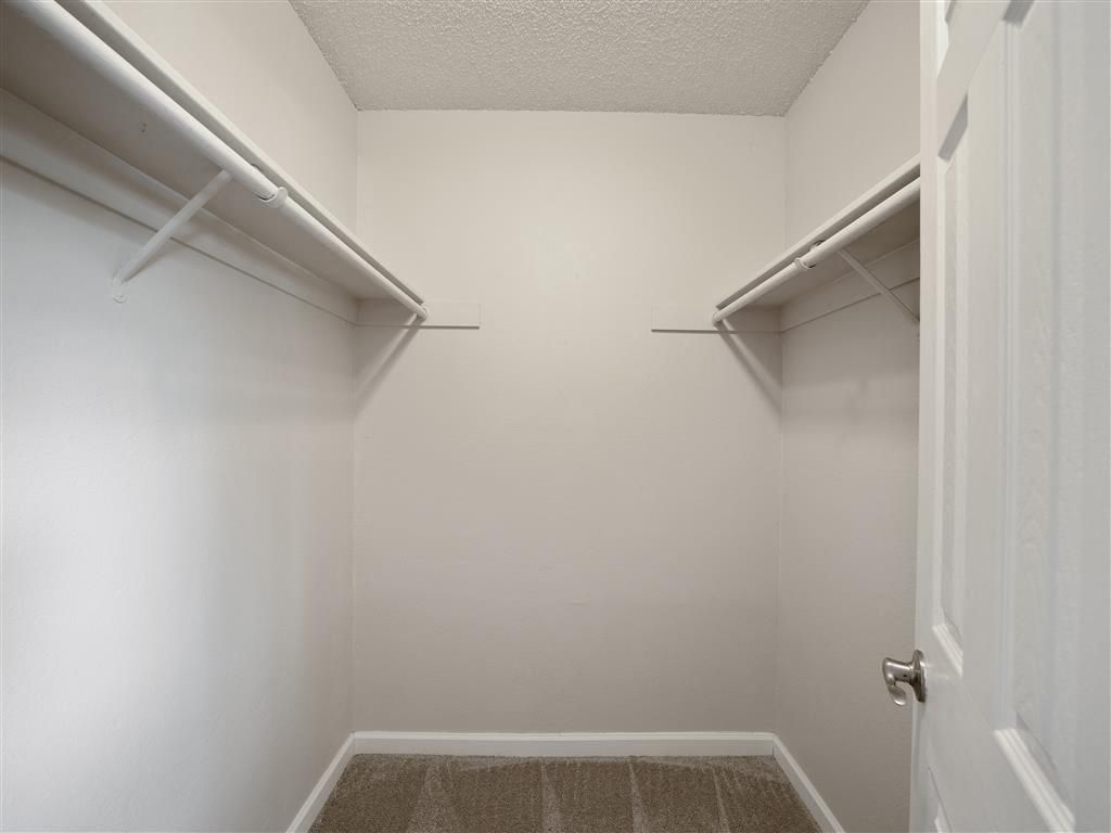 Empty walk-in closet with two clothing rods on each side at Valley Ridge Apartments.