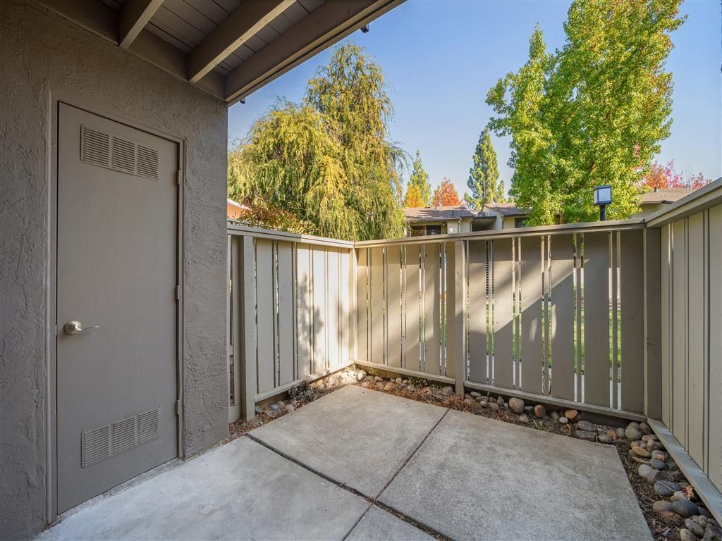 Concrete patio with beige railing and a back door of a ground-floor apartment at Valley Ridge Apartments.