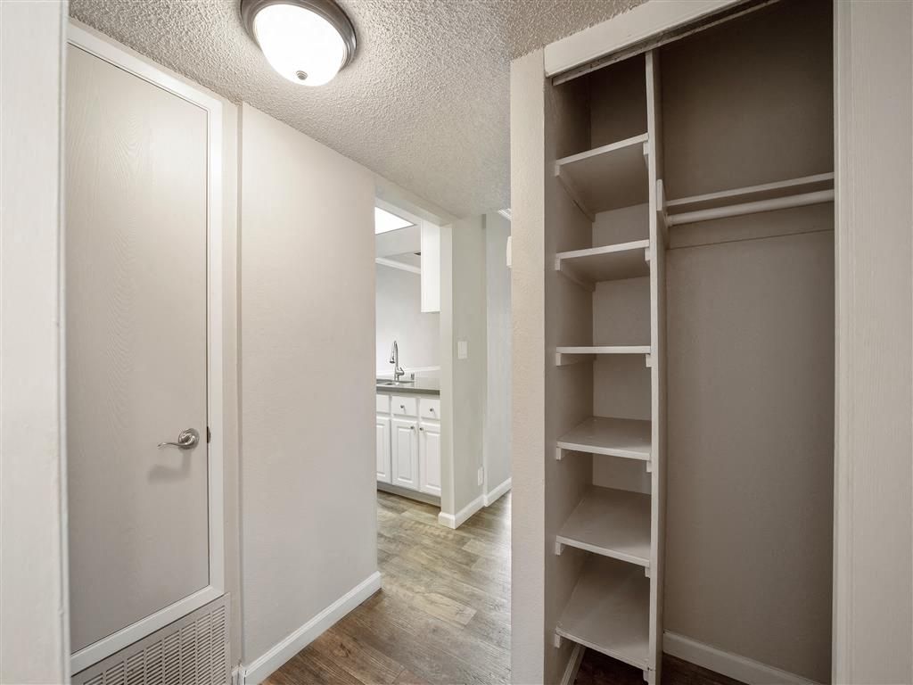 Hallway of an apartment featuring a built-in closet with shelves and a view into the kitchen at Valley Ridge Apartments.