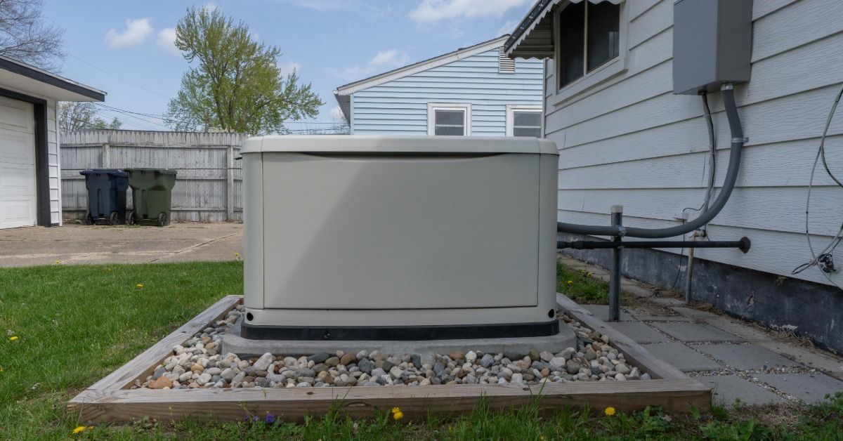 A close-up of a residential standby generator in a home's backyard on a slab surrounded by stones an