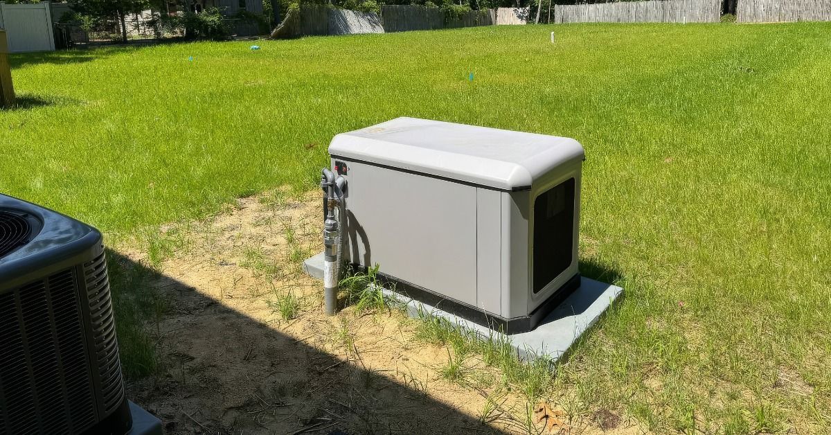 A standby backup generator on a concrete slab next to an air-conditioning unit in the empty backyard
