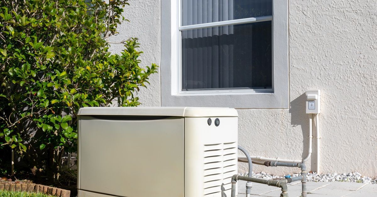 A standby generator sits on a concrete pad beside a home, connected to gas lines and positioned near