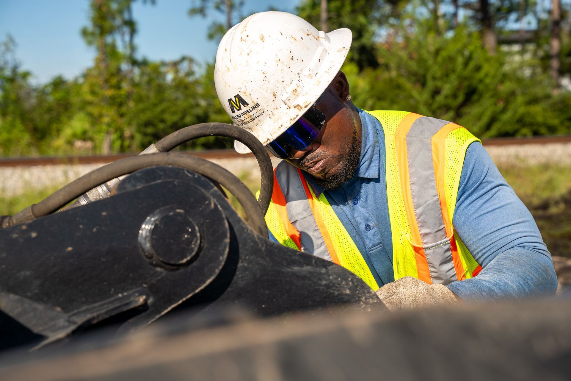 Construction worker in hard hat and safety vest inspecting equipment outdoors